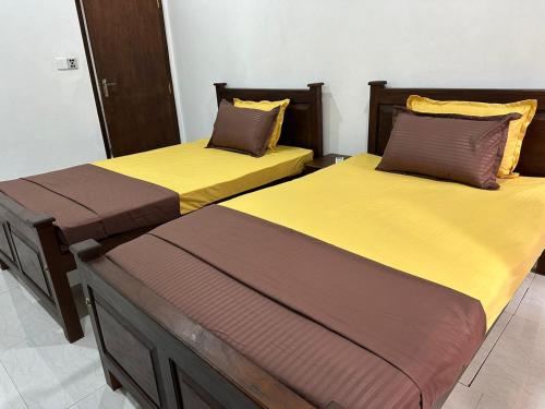 two beds with yellow and brown sheets in a room at The Yellow in Talpe