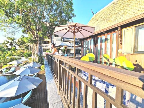 a woman standing on a wooden railing with umbrellas at Buri Sriping Riverside Resort & Spa in Chiang Mai