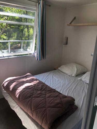 Bett in einem kleinen Zimmer mit Fenster in der Unterkunft Camping Les Terrasses de Dordogne in Rouffignac Saint-Cernin