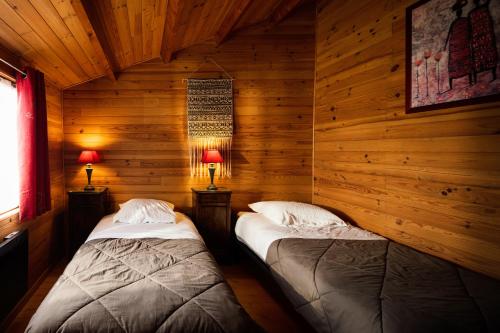 2 camas en una cabaña de madera con 2 lámparas en L'Escale Occitane, en Alzonne