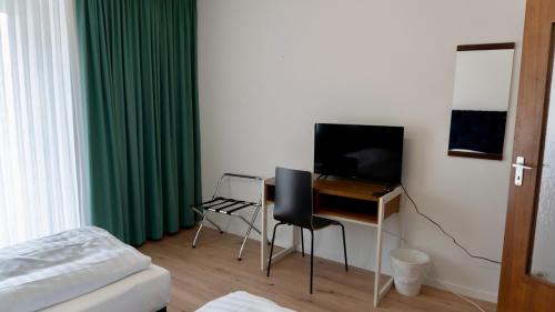 a bedroom with a desk with a television and a bed at Haven - Hotel Am Stadion in Leverkusen