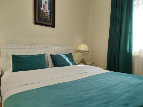 a bed with blue and white sheets and a window at Crown Hotel in Kutaisi