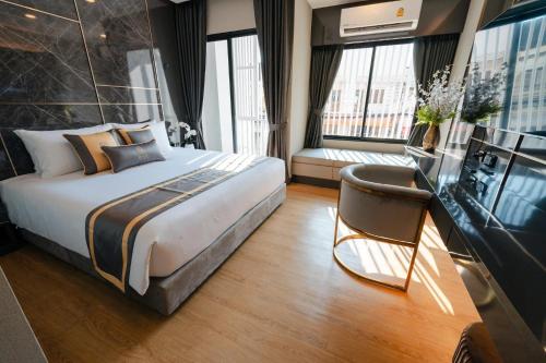 um quarto de hotel com uma cama grande e uma cadeira em Bestier Hotel Hatyai em Hat Yai