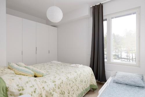 a white bedroom with a bed and a window at New 2BR design home with sauna Espoo Park in Espoo