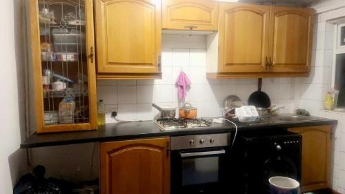 uma cozinha com armários de madeira e um forno com placa de fogão em Numan’s guest house em Coundon