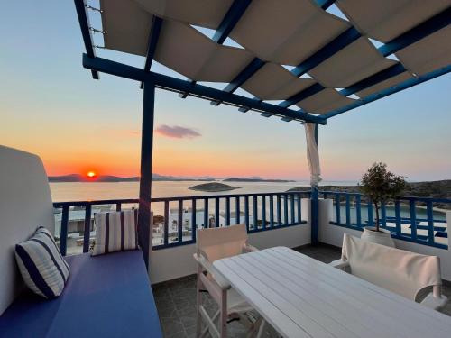 a balcony with a table and chairs and the sunset at Villa Meltemi in Iraklia