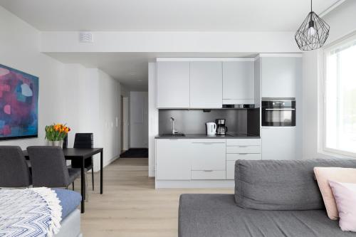 a living room with a table and a kitchen with white cabinets at New 2BR design home with sauna Espoo Park in Espoo