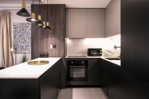 uma cozinha com armários pretos e um balcão branco em Sky View Apartment at Cevahir Sky City 32nd floor em Skopje
