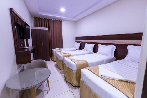a hotel room with three beds and a tv at فندق سجى المصافي Saja almasafi hotel in Makkah