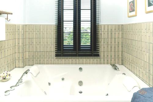 a white bath tub in a bathroom with a window at Buri Sriping Riverside Resort & Spa in Chiang Mai