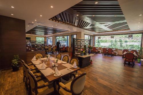 a dining room with a long table and chairs at The Highland Park - A Truly River side Resort in Manāli