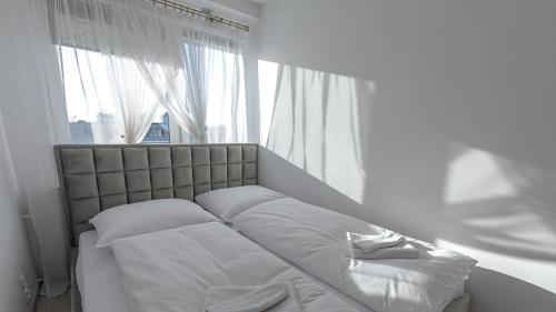 a bedroom with a bed with white sheets and a window at VacationClub – Lwowska 2C Apartament 14 in Kołobrzeg