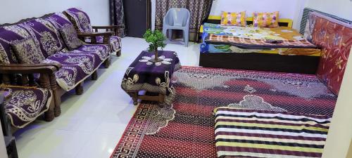 a room with two beds and a table and carpet at chirayu home stay in Ujjain