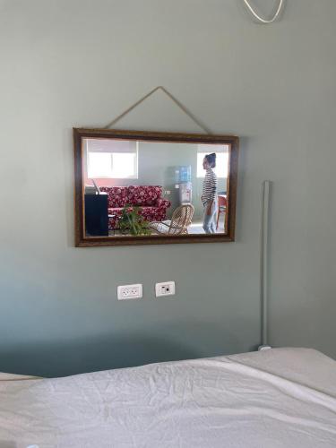 a mirror hanging on a wall above a bed at בין הר ובין ים in Ovnat