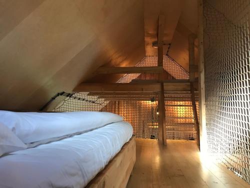 an attic bedroom with a bed and a ladder at Tři domky - tiny houses in Děpoltice