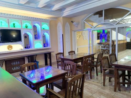 un restaurante con mesas, sillas y TV en Sarbon Plaza Hotel, en Bukhara