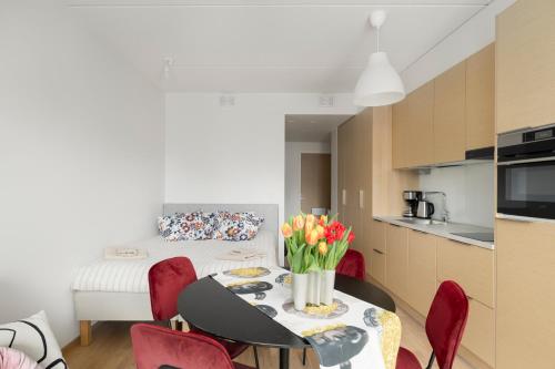 einen Esstisch mit roten Stühlen und eine Küche in der Unterkunft Sea View Design Studio near metro in Espoo