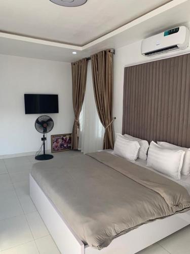 a bedroom with a large bed and a flat screen tv at 4 bedroom Luxury Duplex in Lekki