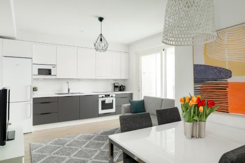 Modern LUXUS 3BR apartment Helsinki Tripla في هلسنكي: مطبخ وغرفة معيشة مع طاولة وكراسي