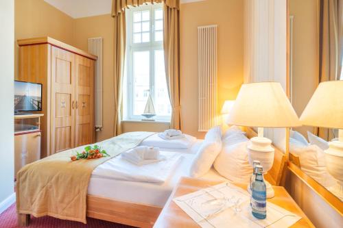 a bedroom with a large white bed and a window at Strandhotel Möwe in Bansin