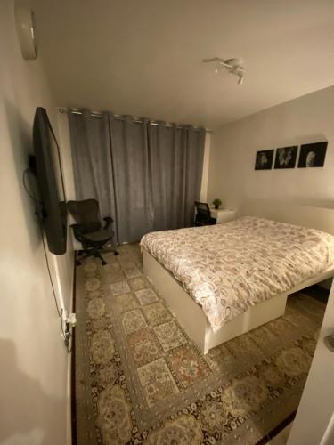 Un dormitorio con una cama y un televisor de pantalla plana. en One Bedroom Flat in Chiswick W4, en Londres