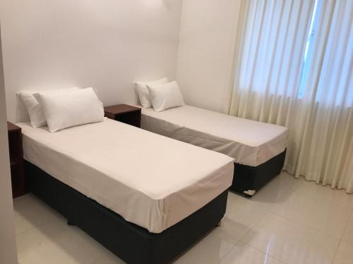 two beds in a small room with a window at Luxe Beach Pad in Wattala