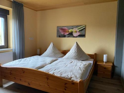 1 dormitorio con cama de madera con sábanas blancas en Ferienwohnung Burgberg, en Stadtkyll