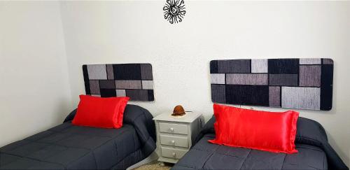 a bedroom with two beds with red pillows and a clock at Alojamiento Maria in Pinos Genil