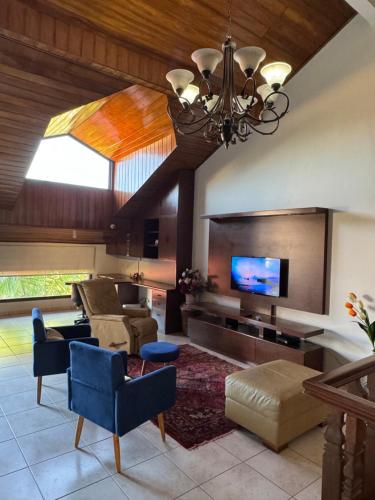 uma ampla sala de estar com uma televisão e um lustre em Hermosa casa amplia en zona residencial em Santa Cruz de la Sierra
