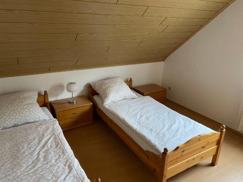 2 łóżka pojedyncze w pokoju z drewnianym sufitem w obiekcie Ferienwohnung Klara w mieście Meßstetten
