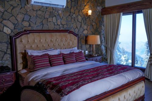 a bedroom with a large bed with a stone wall at Cedar Lodges Resort and Residences Galiyat in Chhāngla Gali