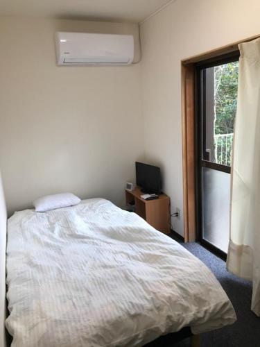 1 dormitorio con cama y ventana en Hostel John Mang ゲストハウス ジョン, en Tosa