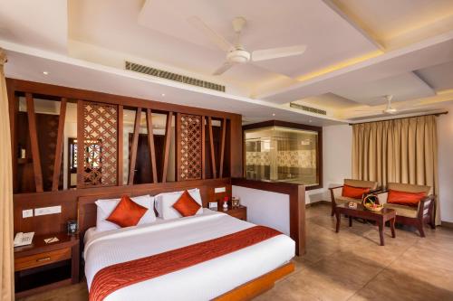 une chambre d'hôtel avec un lit et une chaise dans l'établissement Lake Canopy Alleppey, à Mararikulam