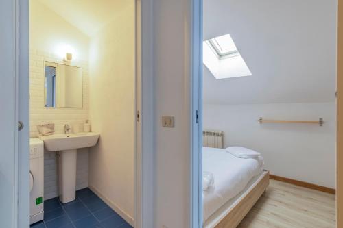 a bathroom with a bed and a sink and a mirror at [IHost Apartment] - Adige 17 in Milan
