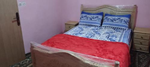 a bed with a red and blue comforter and pillows at Welkom ketama bro hotil hassan in Ketama