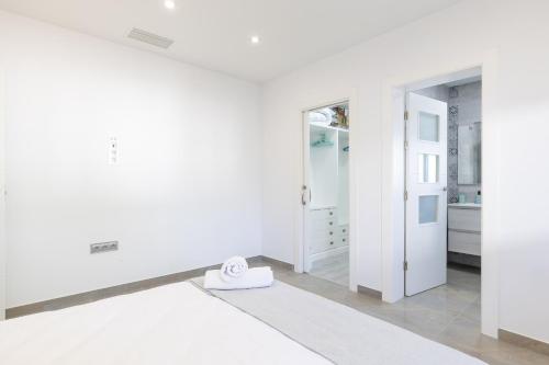 een witte kamer met een klok op de vloer bij WaterWheel Villa by Fidalsa in Almoradí