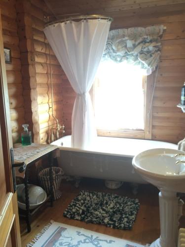 a bathroom with a tub and a window and a sink at Balnabrechan Lodge in Arbroath