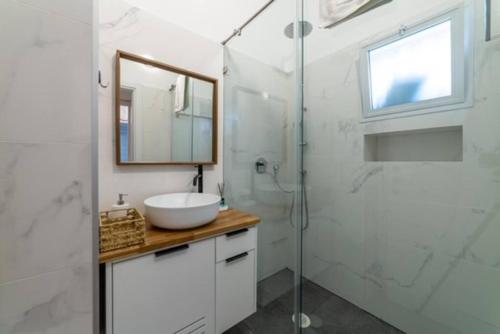 y baño con lavabo y ducha acristalada. en Modern 2br 6 guets - ben gourion Blvd area en Tel Aviv