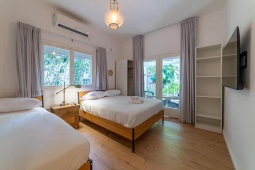 a bedroom with two beds and a large window at Modern 2br 6 guets - ben gourion Blvd area in Tel Aviv