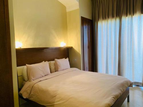- une chambre avec un lit doté de draps blancs et une fenêtre dans l'établissement Villa de standing à Marrakech Complexe résidentiel Apple Garden, à Marrakech