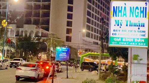 een drukke stadsstraat 's nachts met auto's en een bord bij Nhà Nghỉ MỸ THUẬN in Long Hai