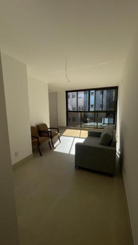 ein Wohnzimmer mit einem Sofa und einem großen Fenster in der Unterkunft Apto JP 301 para 2 pessoas in Vitória