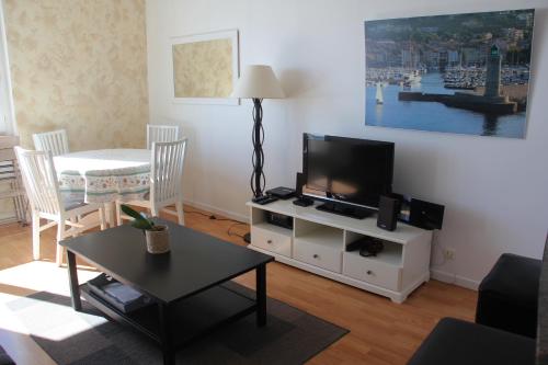 a living room with a flat screen tv and a table at Picouveau in Cassis