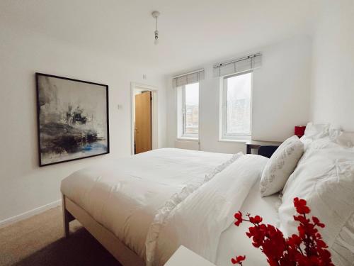 a white bedroom with a large white bed with red flowers at Specious en-suite room - a cosy homestay close to Tower Bridge in London