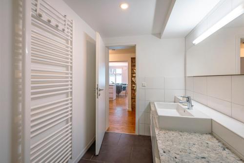 a white bathroom with a sink and a mirror at Haus Triflinger in Lindau