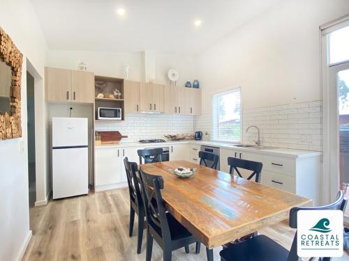 a kitchen with a wooden table and a white refrigerator at The Purple Hen Hideaway Resort in Cowes