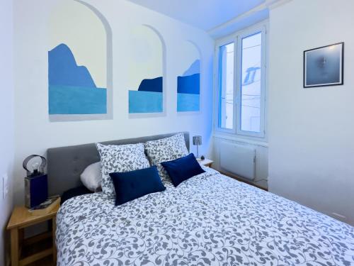 a bedroom with a large bed with blue pillows at ART appartement climatisé, 3 chambres, 5 lits, 1 min du port, cuisine équipée and jeux de société in Port-Vendres