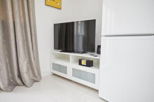 a white entertainment center with a tv and a curtain at Spire View Apartment*SO15 Sleeps 4-Secure Parking in Southampton