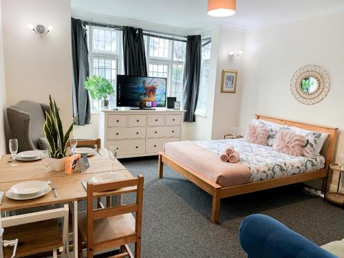 a bedroom with a bed and a table and a tv at Cosy Apartments Near Hampstead Heath With Free On-Site Parking & Private Gardens, Golders Green in London