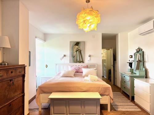 a bedroom with a bed and a yellow chandelier at Pequeno Paraiso-1RoomLet in São Brás de Alportel